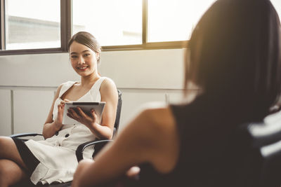 Portrait of a smiling young woman using phone