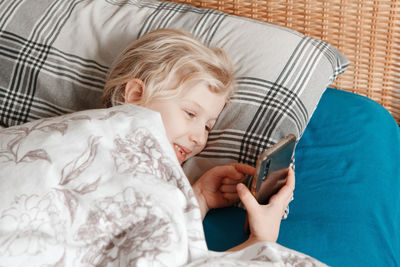 Midsection of woman using mobile phone while relaxing on bed