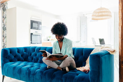 Young woman using phone while sitting on sofa at home