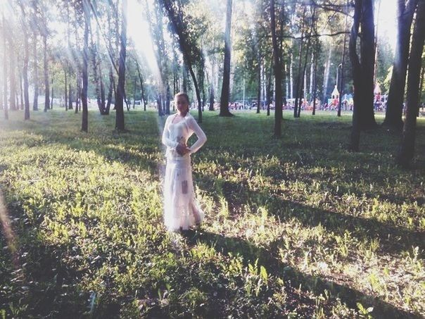 tree, young adult, grass, person, lifestyles, sunlight, leisure activity, front view, young women, tree trunk, looking at camera, park - man made space, casual clothing, growth, portrait, field, sunbeam, day