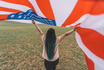 Rear view of woman holding american flag outdoors