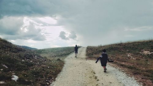 Rear view of men walking on mountain against sky