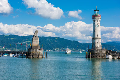 Lighthouse on building by sea against sky