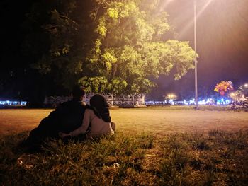 Rear view of couple sitting on grass at night