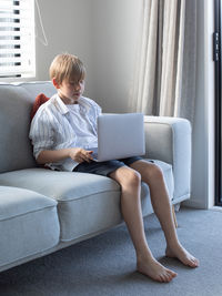 Boy using laptop while sitting on sofa at home
