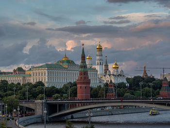 Spasskaya tower by moscva river against cloudy sky