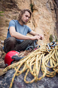 Young man sitting on rope