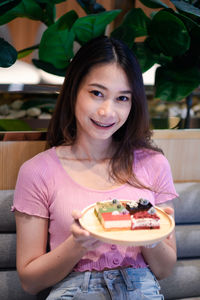 Portrait of smiling young woman having food at home