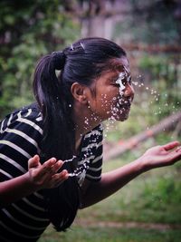 Young woman washing face with water