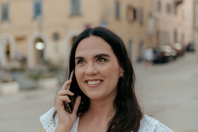 Candid portrait of happy young woman talking on the phone in city