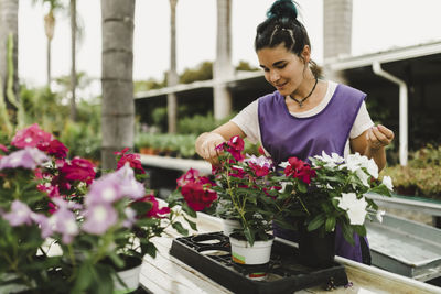 Mid adult businesswoman examining flowering plants at nursery