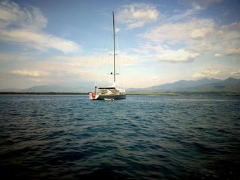 Boat sailing in sea against cloudy sky
