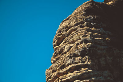 Low angle view of rock formation against clear blue sky