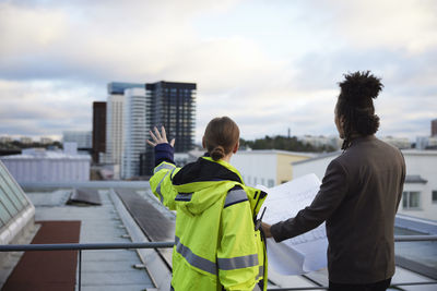 Architects talking while holding blueprints