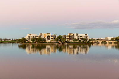 Buildings by lake against sky in city