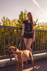 Young woman standing with dog on footbridge