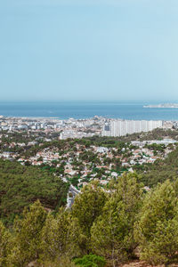 High angle view of cityscape by sea against clear sky