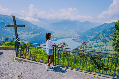 Woman standing on railing against mountains