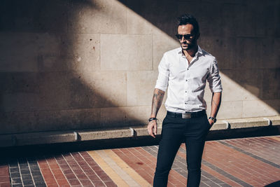 Portrait of young man standing against wall