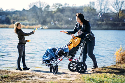 Happy family, mother, daughter and son with cerebral palsy spending time together on the river bank