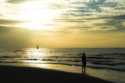 Silhouette man standing on beach against sky during sunset