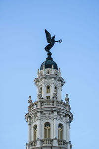 Low angle view of statue of building against blue sky