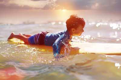 Rear view of boy in sea against sky