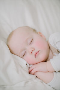 Closeup of sleeping baby girl's face in white bed