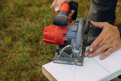 Midsection of carpenter using circular saw on wood