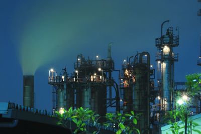 Illuminated factory against sky at night