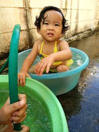 Portrait of girl with person sitting in bathtub outdoors