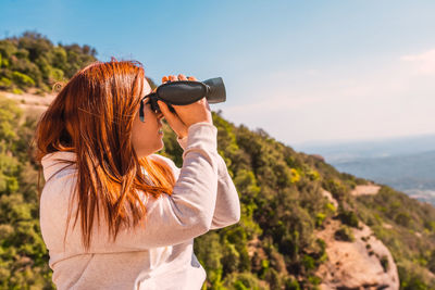 Woman looking through binocular sitting outdoors