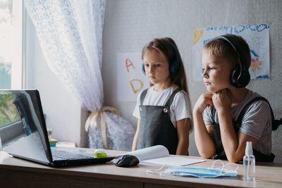 Cute siblings looking at laptop during online lecture