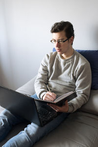 Young man using laptop while sitting on sofa at home