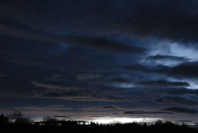 Low angle view of silhouette trees against dramatic sky