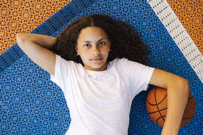 Directly above portrait of girl with basketball lying on court