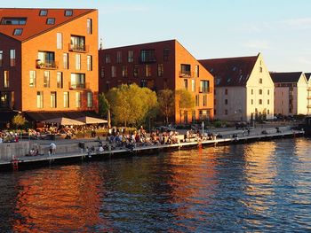 Buildings by river against sky