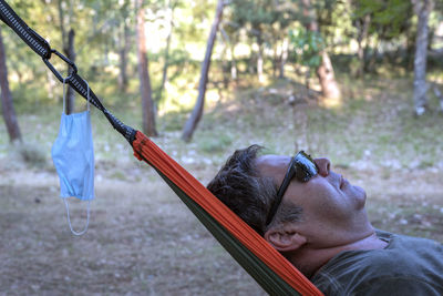 Portrait of young man holding swing in playground