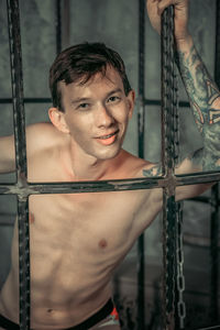 Portrait of a young man standing in a cage