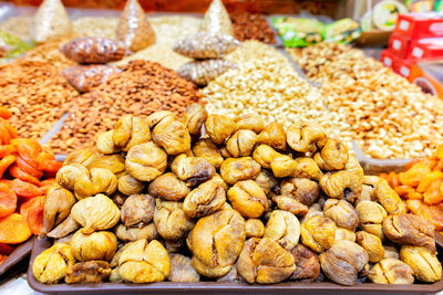 A slide of ugly dried figs is sold on the market amid various nuts in blur.