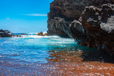 Rock formation in sea against sky