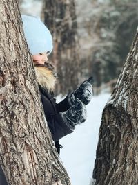 Little girl on tree trunk during winter