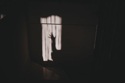 Shadow of hand on window at home