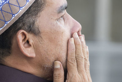 Close-up of mature man praying while sitting at mosque