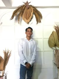 Portrait of young man standing against wall