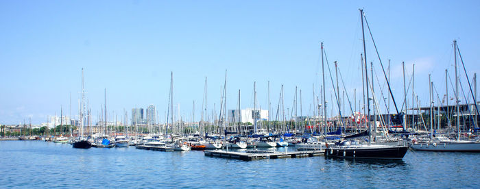 Boats moored in harbor against blue sky