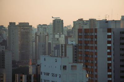 Buildings in city against clear sky at dusk