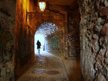 Rear view of man walking in alley amidst buildings