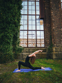 Woman stretching on field against large window