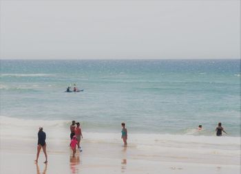 People on beach against clear sky